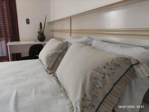 a bedroom with a white bed with two pillows at Pousada com vista para o Cristo 4 in Encantado