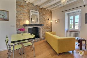 a living room with a yellow chair and a table and a fireplace at Le presbytere in Plouaret