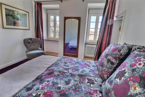 a bedroom with a bed and a chair and windows at Le presbytere in Plouaret