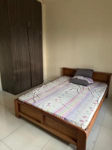 uma cama com uma moldura de madeira e um armário num quarto em Kams Lodge Broadview, Idu em Furah
