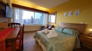 a bedroom with a bed and a couch and a window at Dto Triskel con vista al lago in San Carlos de Bariloche