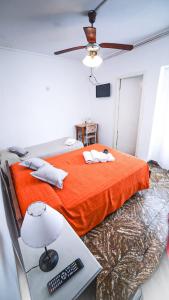 a bedroom with an orange bed and a desk with a lamp at Hotel Parque in Necochea