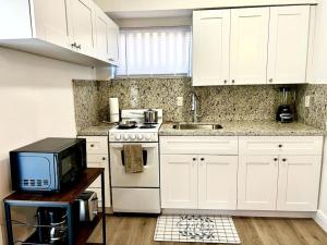 a kitchen with white cabinets and a microwave at Intimate Casita Mia minutes away from Airport, Calle 8, Brickell, Coral Gables, The beach and more! in Miami