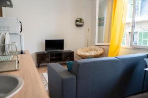sala de estar con sofá azul y TV en YELLOW HOME, en Fougères