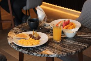 a table with two plates of food and a glass of orange juice at Ontico Urban Design Hotel in Mérida