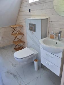 a white bathroom with a toilet and a sink at Kolonijna Park in Międzyzdroje