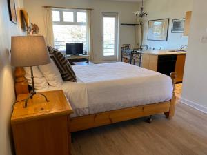 1 dormitorio con 1 cama y 1 mesa con lámpara en Island Village Properties at Fred Tibbs, en Tofino