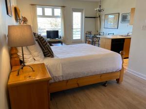 a bedroom with a bed and a table with a lamp at Island Village Properties at Fred Tibbs in Tofino