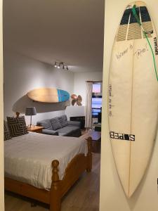 a surfboard hanging on a wall next to a bedroom at Island Village Properties at Fred Tibbs in Tofino
