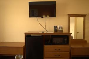 a tv on top of a wooden cabinet with a microwave at Key West Inn - Chatsworth in Chatsworth