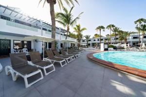 a resort pool with lounge chairs and a swimming pool at Labranda Playa Club in Puerto del Carmen