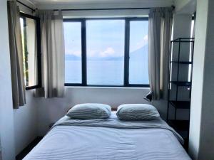 a bed with two pillows in a room with a window at Rustic Charm Cliffside Retreat in Jaibalito