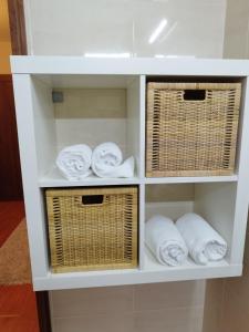 a white shelf with wicker baskets and towels at Aconchego do Lar in Geres