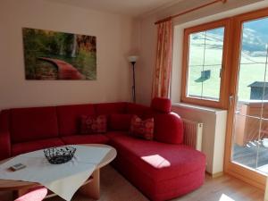 een woonkamer met een rode bank en een tafel bij Apart Studio Bergdiamant in Piösmes