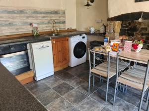 een keuken met een wasmachine en een tafel bij Tea Cosy Cottage in Bude