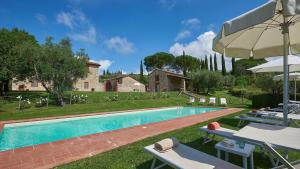 a pool with chairs and umbrellas next to a house at San Demetrio in Castelnuovo Berardenga