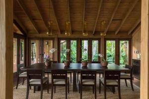 comedor con mesa, sillas y ventanas en Sunny Vacation Villa No 34, en Bonao