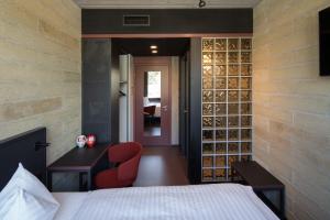 1 dormitorio con cama, escritorio y pared con botellas de vino en Tailormade Hotel LEO St Gallen, en St. Gallen