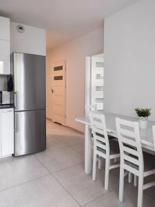 cocina con mesa, sillas blancas y nevera en Apartment Szwed-Sniadowskiej Residence, en Cracovia