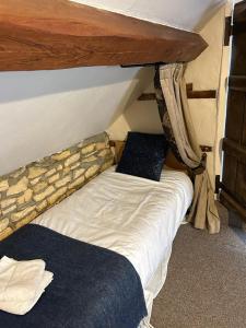a bed in a room with a stone wall at Siam cottage guesthouse over 300 years old with Thai restaurant in Moreton in Marsh +99 photos