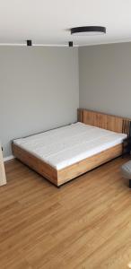 Bett in einem Zimmer mit Holzboden in der Unterkunft Słoneczny apartament in Augustów