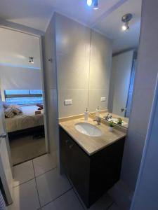 a bathroom with a sink and a large mirror at Acogedor y cómodo depto. 2d+2b in Los Ángeles