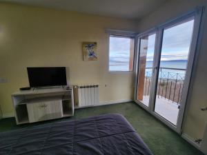 a bedroom with a bed and a television and a balcony at Mirabeagle Departamentos in Ushuaia