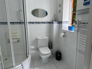 a white bathroom with a toilet and a shower at The Garden Suite in Basingstoke