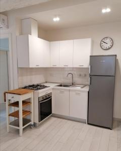 een keuken met witte kasten, een wastafel en een koelkast bij Appartamento La Corte in Forte dei Marmi