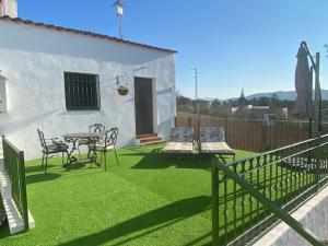 un patio con mesa y sillas en el césped en La Casa Palmera - Caminito Del Rey, en Pizarra