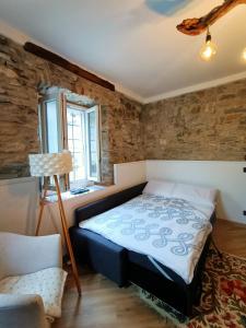 a bedroom with a bed and a chair and a window at casa Virginia nel borgo in Lierna