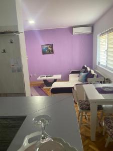 ein Wohnzimmer mit lilafarbenen Wänden und einem Tisch in der Unterkunft Apartmani Marić In in Vrnjačka Banja