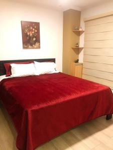 Un dormitorio con una cama con una manta roja. en Condominio La Victoria, departamento, en Cuenca