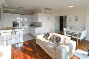 a living room with a white couch and a kitchen at Apartman TRSAT in Rijeka