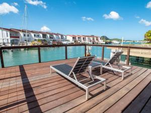 2 sillas sentadas en una terraza de madera junto al agua en Crystal Waters - Modern Waterfront Villa - King Sized Bed - 235E, en Jolly Harbour
