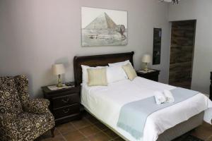 a bedroom with a large bed and a chair at Khutse Guest House in Lephalale
