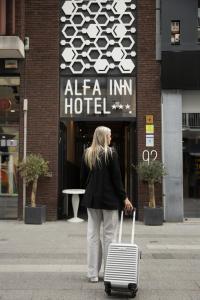 Uma mulher a andar numa rua com uma mala. em Alfa Inn em Blankenberge