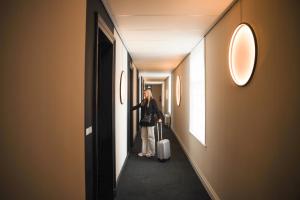 a woman walking down a hallway with a suitcase at Alfa Inn in Blankenberge
