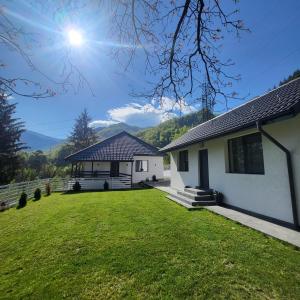 ein weißes Haus mit grünem Rasen davor in der Unterkunft White Story in Brezoi