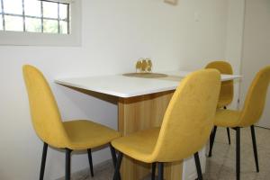 Una mesa con sillas amarillas y un mostrador blanco. en Golden Kosher Suite, en Kefar Weradim