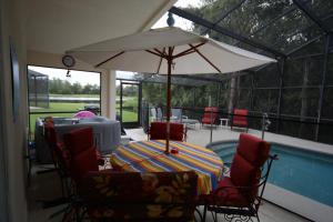 een tafel en stoelen met een parasol naast een zwembad bij Elite Homes - Cumbrian Lakes in Kissimmee