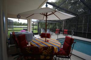 a table and chairs with an umbrella next to a pool at Elite Homes - Cumbrian Lakes in Kissimmee