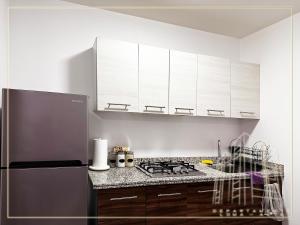 cocina con armarios blancos y nevera de acero inoxidable en Departamento Loma-Alta en Guadalajara