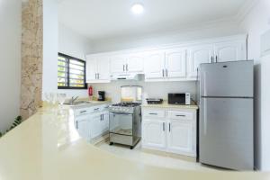 cocina con armarios blancos y nevera de acero inoxidable en MB Apartment - A en San Felipe de Puerto Plata