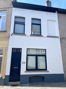 a white house with a blue door and windows at Studio Cosy à Woluwé in Brussels