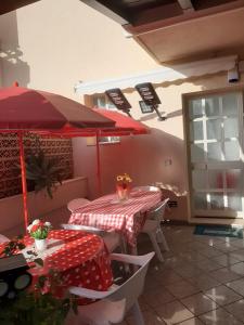 uma mesa com um guarda-chuva vermelho num pátio em Casa del sole e del mare em Marina di Ragusa