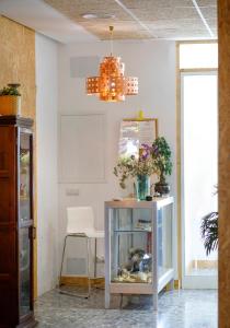 Habitación con mesa, pecera y lámpara de araña. en Italica Hostel, en Santiponce