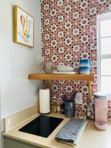 um balcão de cozinha com um lavatório e uma parede de azulejos em The Cherry Blossom em Sanford