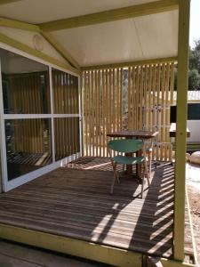 una terraza de madera con mesa y silla en Grande Chambre tout confort 3, en Bonifacio