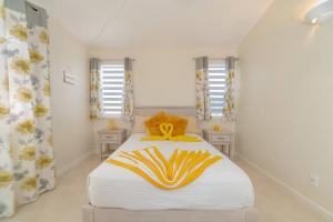 a bedroom with a large bed with yellow and white sheets at Attractive 3-Bedroom Home - Harbour Breeze in Jolly Harbour